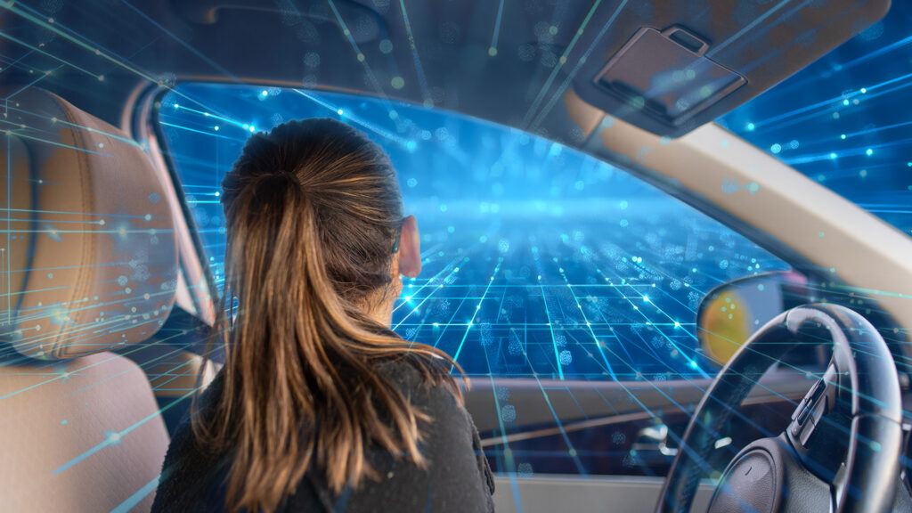 Woman in her car looking out her driver's side window and seeing nothing but technology.